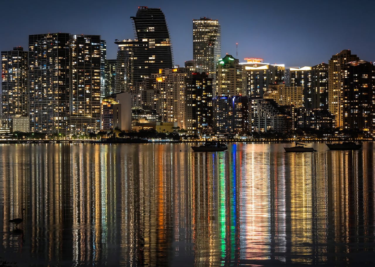 Home Captivating night view of Miami skyline with dazzling reflections on the water, showcasing city lights.